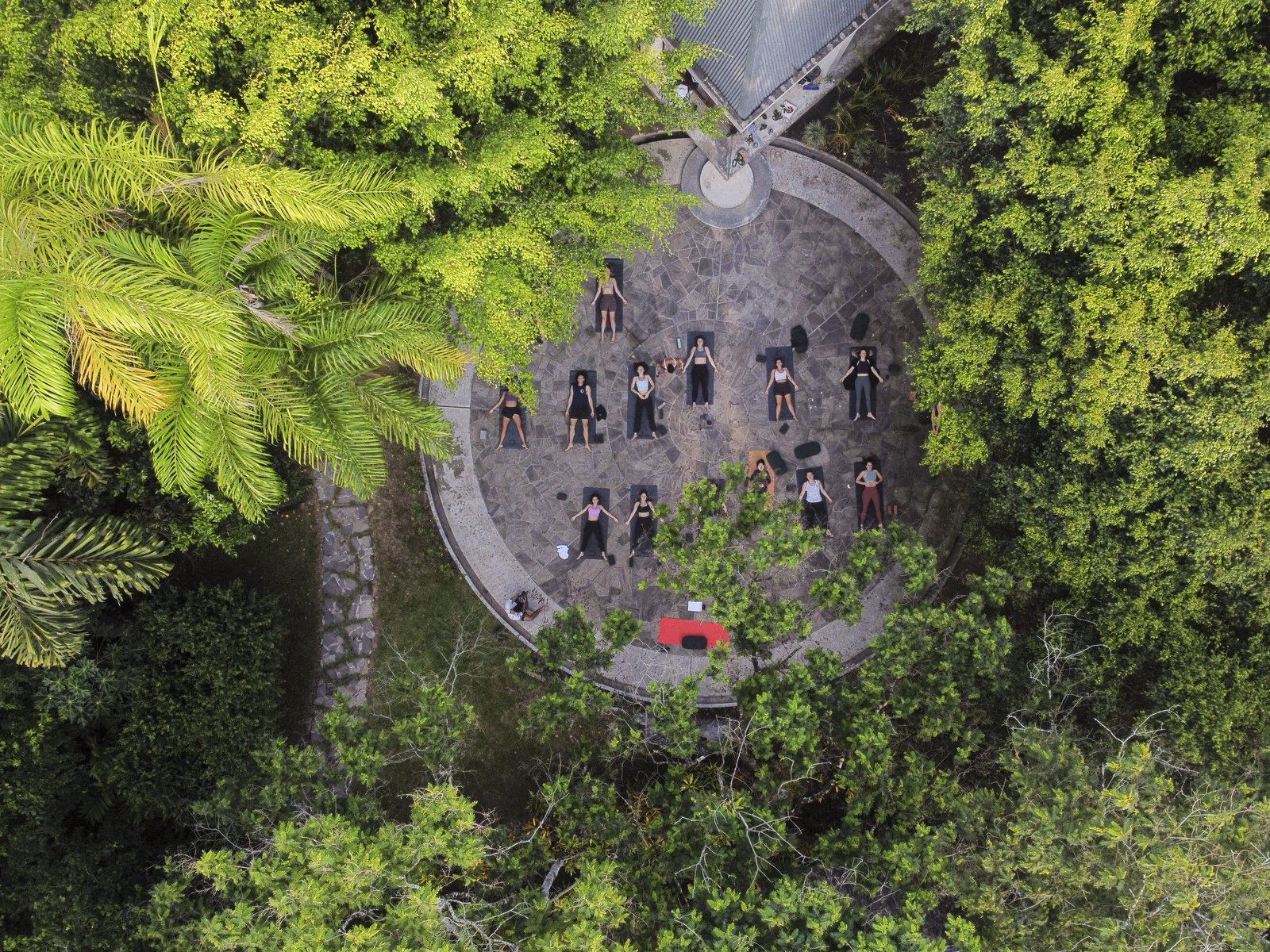 Aerial drone view of yogis lying in savasana in a circle at Kantu Garden Lodge — Moksha Yoga Amazónica retreat in the Peruvian Amazon