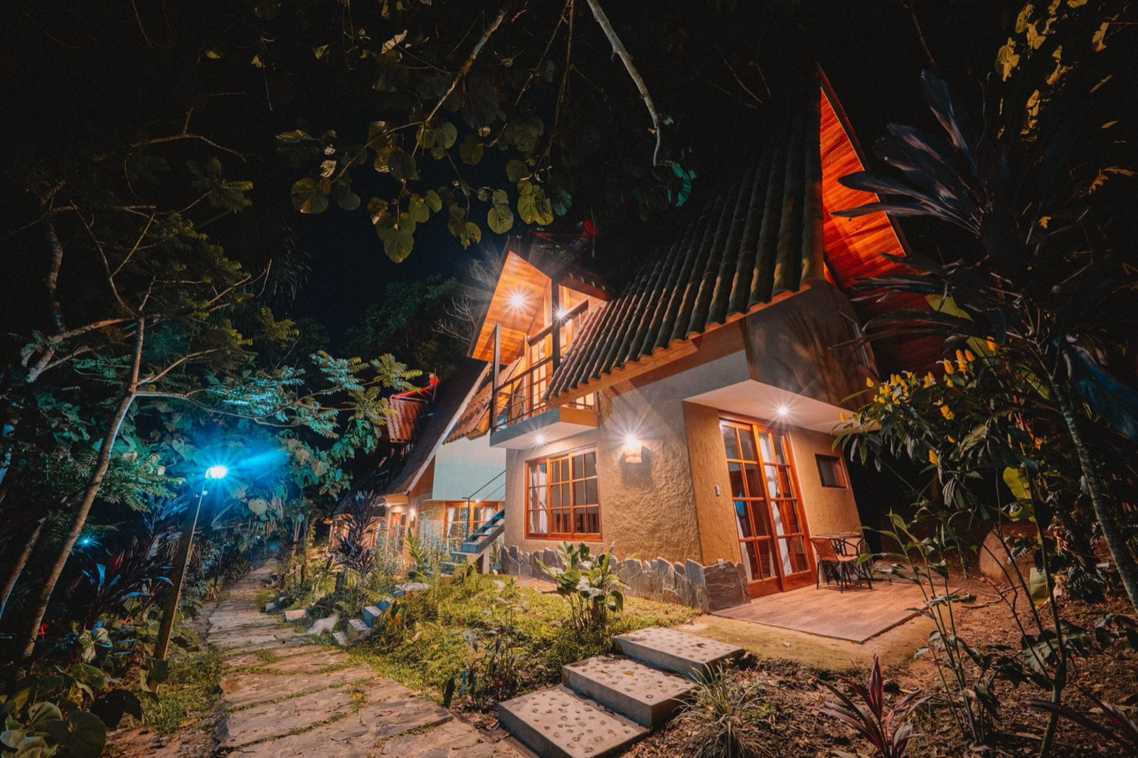 A bungalow at Kantu Garden Lodge at night, warm interior lights through the windows