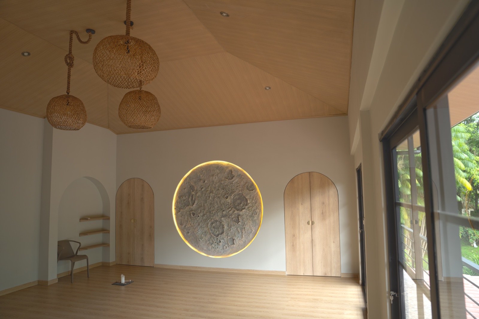 Side angle of the new practice room — two woven-rattan pendants on rope, the vaulted cedar ceiling rising overhead, and the glass doors that open to the garden
